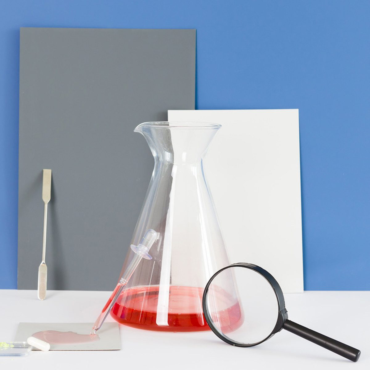 collage of a lab beaker and laminate samples with a magnifying glass